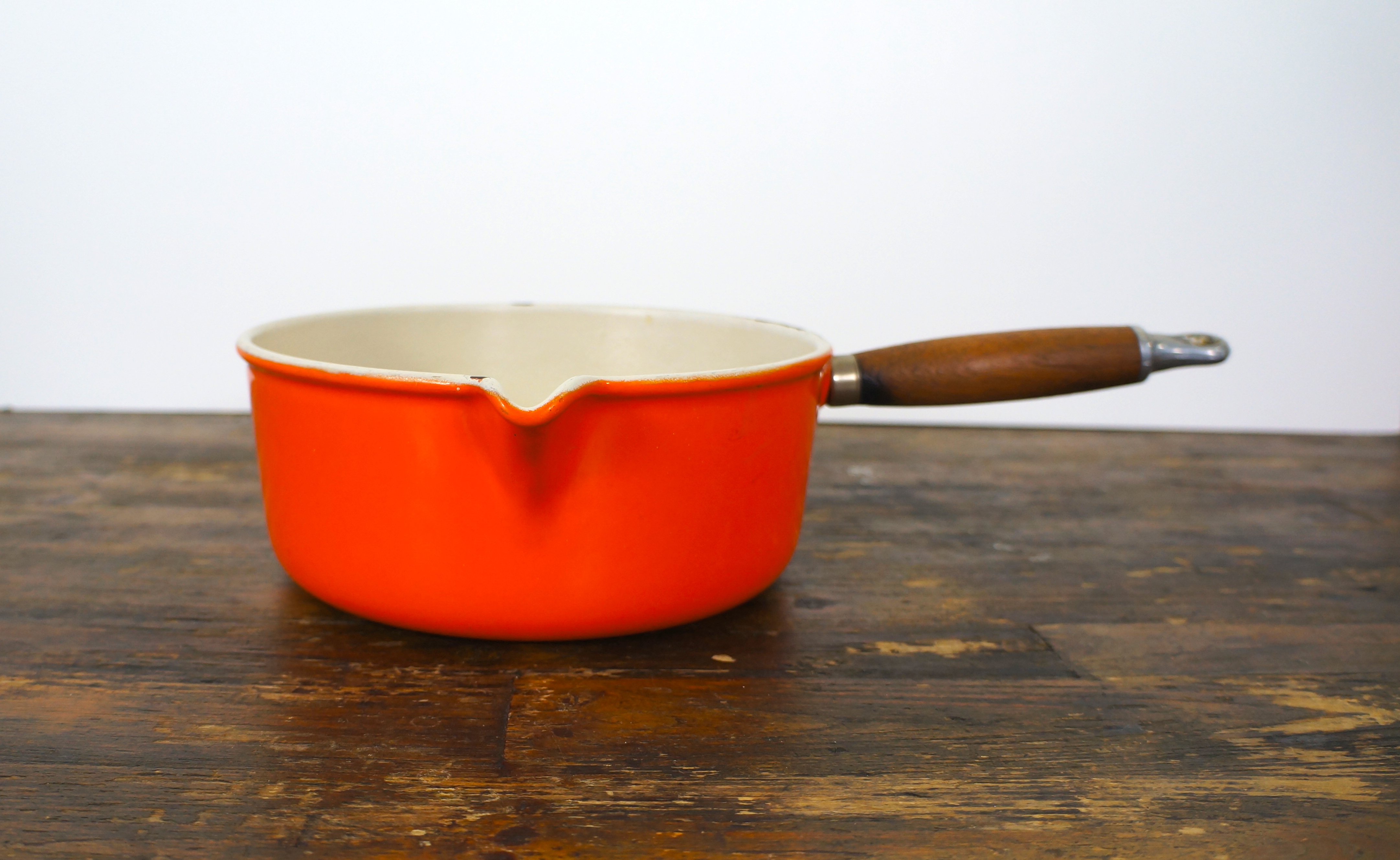 Oranje gietijzeren steelpan le creuset met schenktuit en houten ...